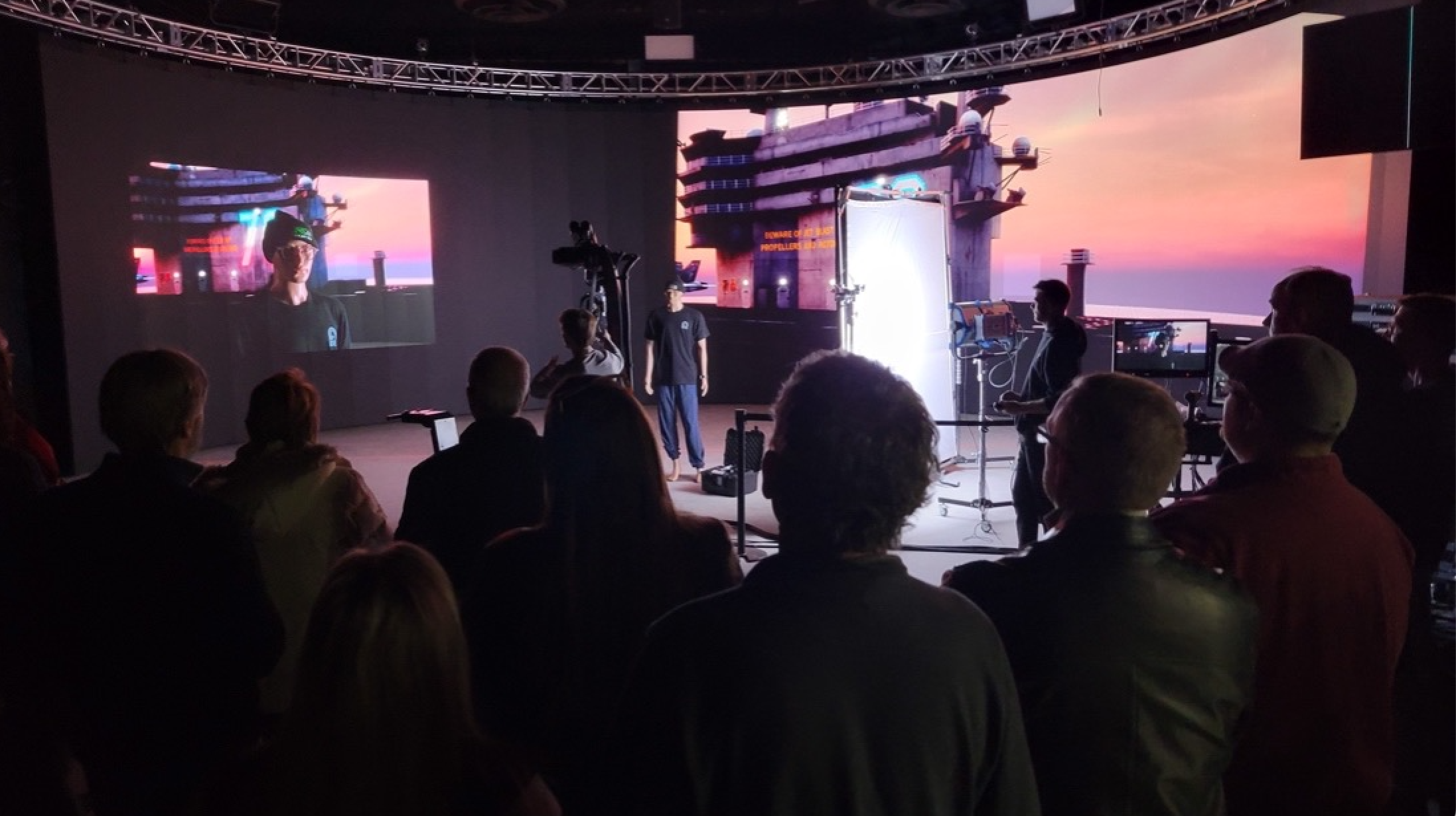 Actor being filmed in a New Hampshire based professional video production studio with a crowd watching and standing behind the camera.