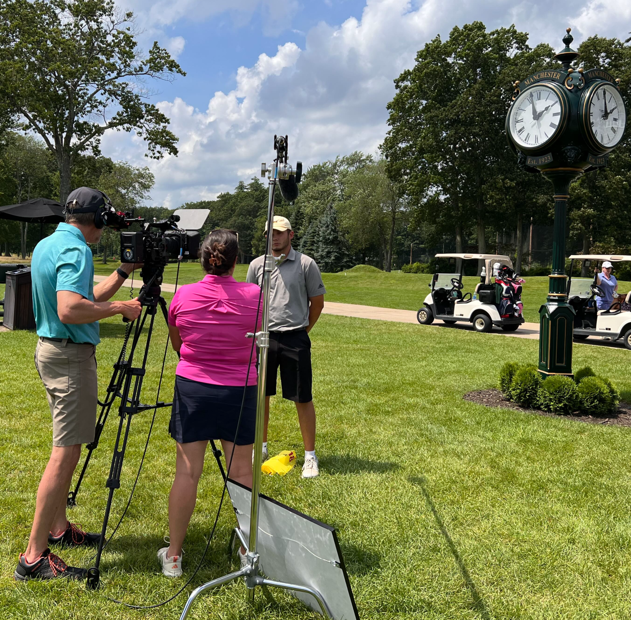 Granite River Studios crew on set of a film shooting location interviewing a golfer with golfs carts behind him.